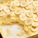 Bowl of homemade banana pudding with custard, bananas and Nilla wafers topped with meringue.