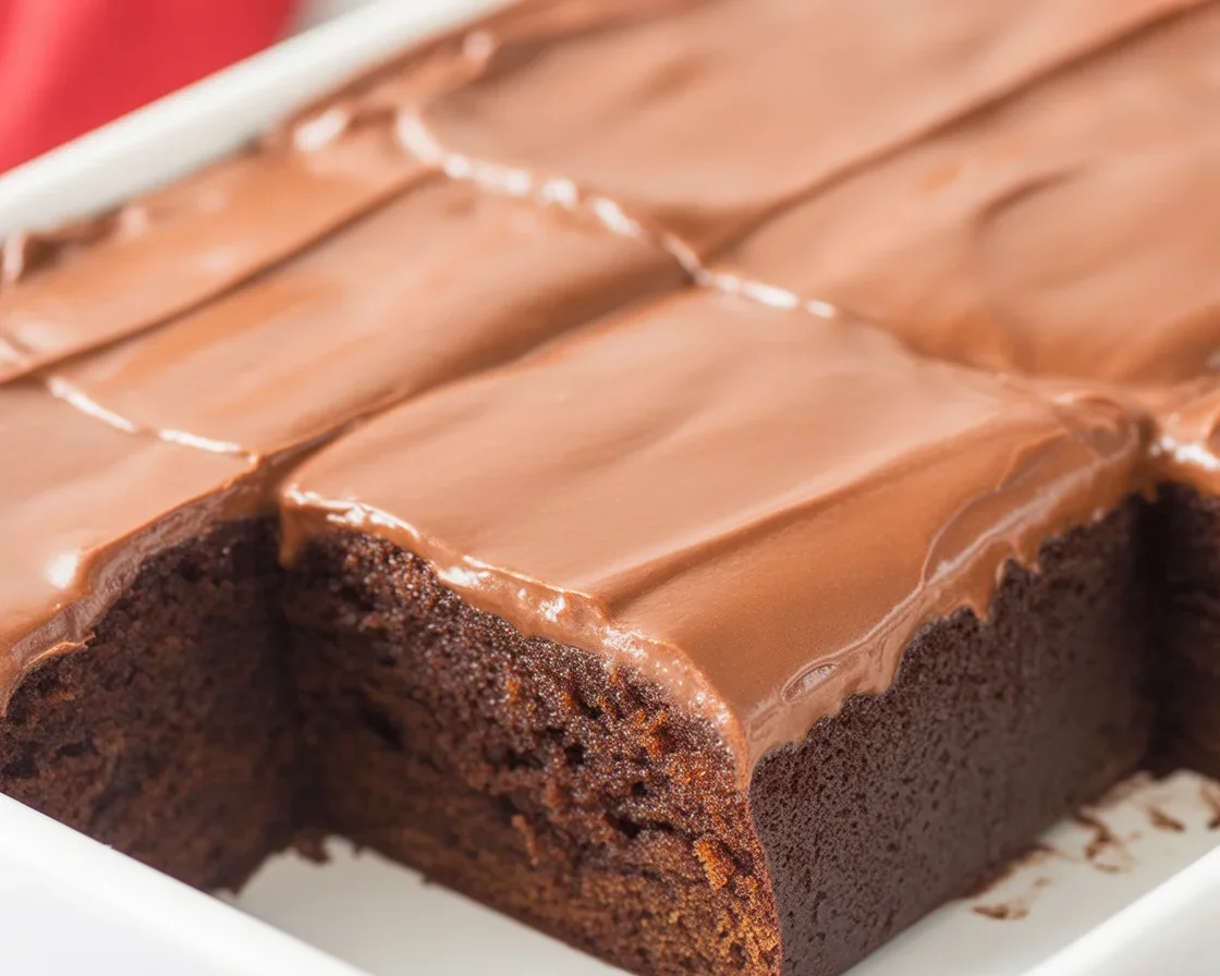 Deliciously moist Coca Cola cake with chocolate frosting served on a plate.