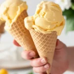 Creamy mango ice cream topped with fresh mango slices served in a bowl.