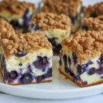 Moist blueberry coffee cake topped with cinnamon streusel served on a plate.